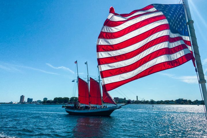 a flag on the back of a boat next to a body of water