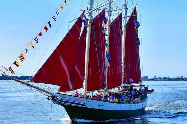 Sailing ship with red sails and decorative flags on a sunny day.